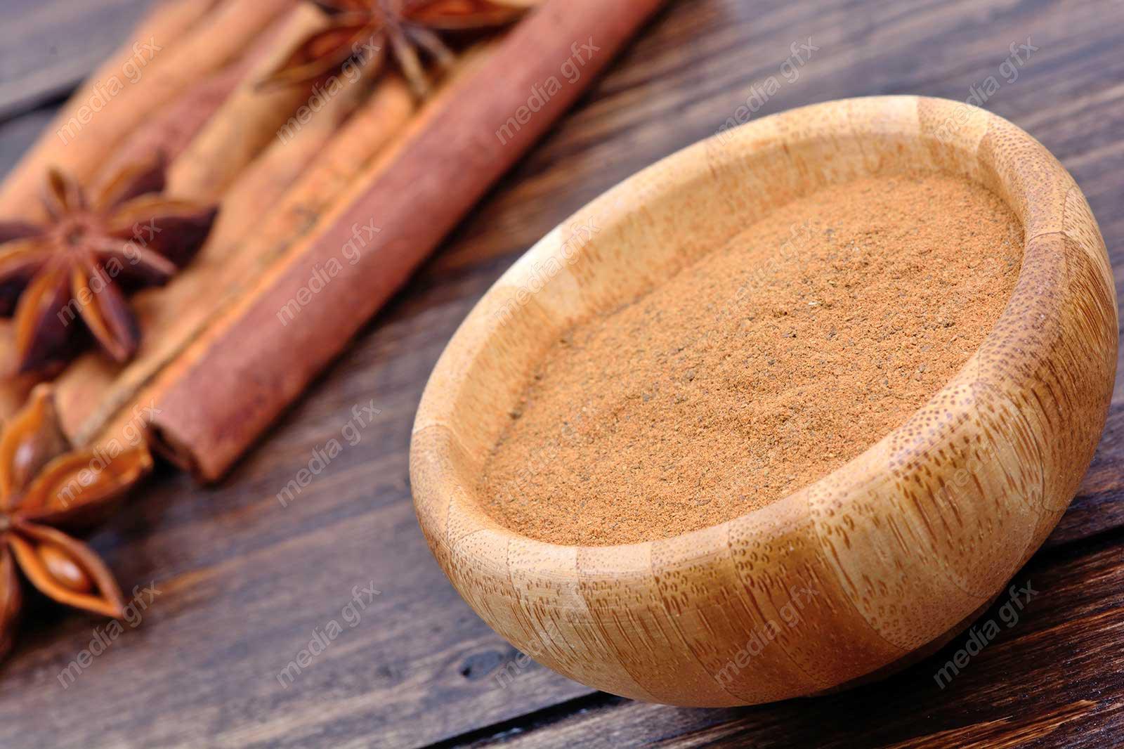 عکس با کیفیت چوب دارچین و پودر دارچین روی میز چوبی MJ004745